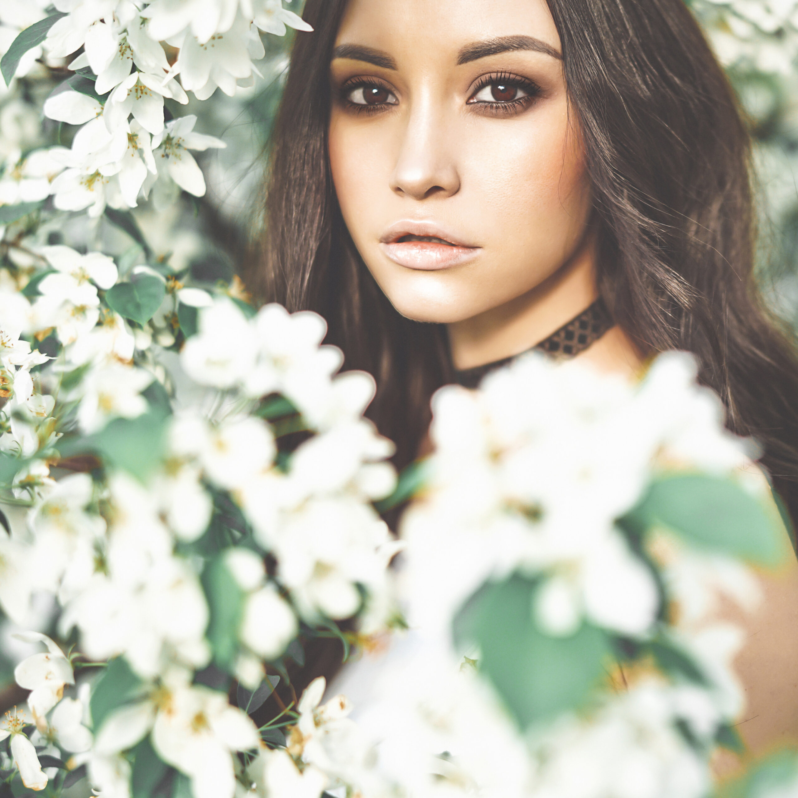 Beautiful young woman surrounded by flowers of apple-tree